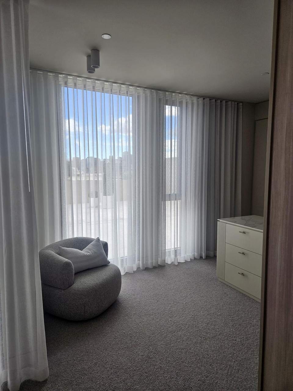 Sheer curtains over a bedroom sliding door with a garden view