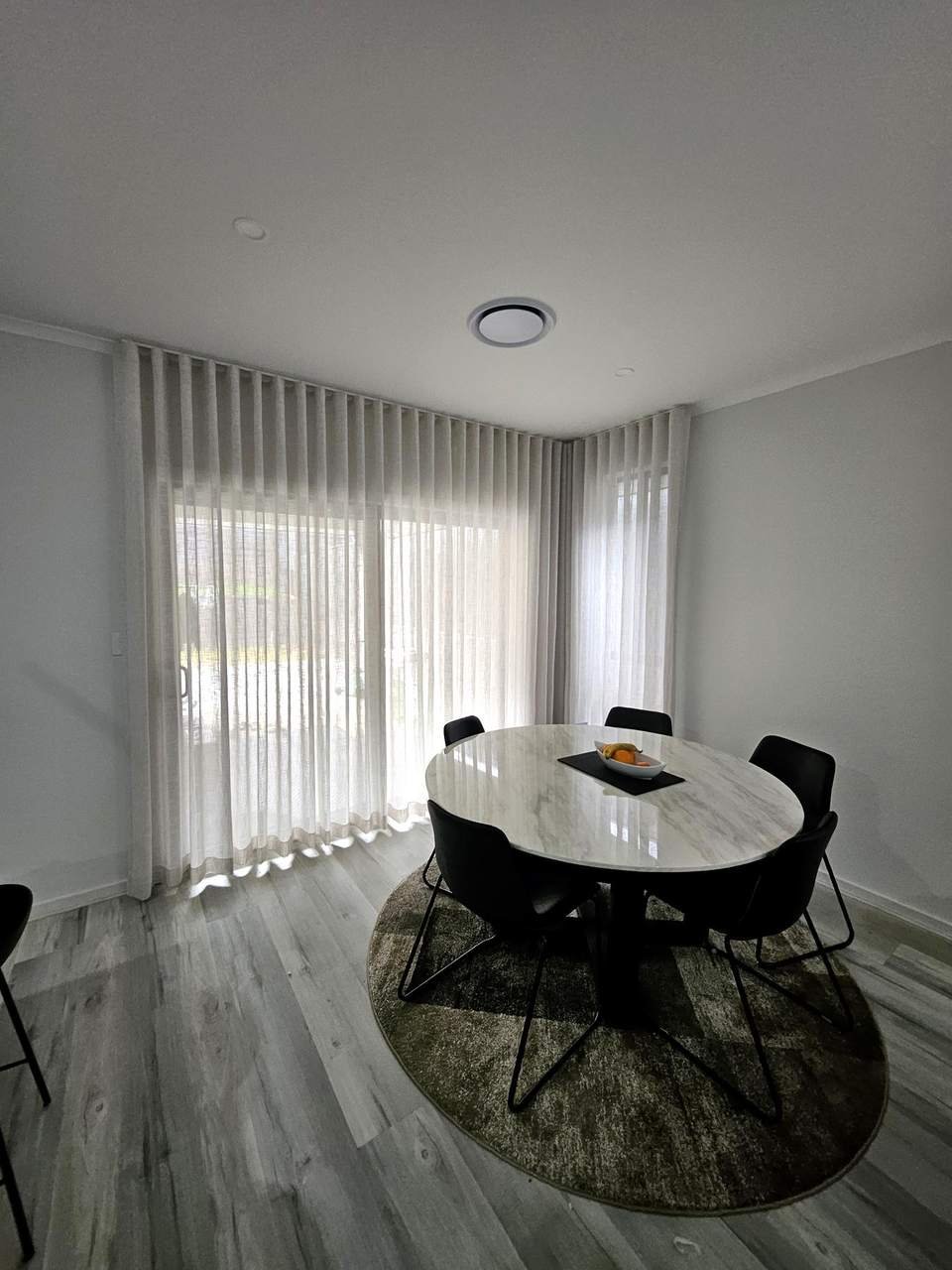 Sheer curtains behind a round dining table