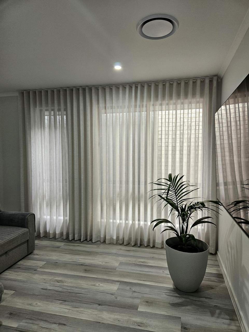 Sheer curtains in a living room with a grey sofa