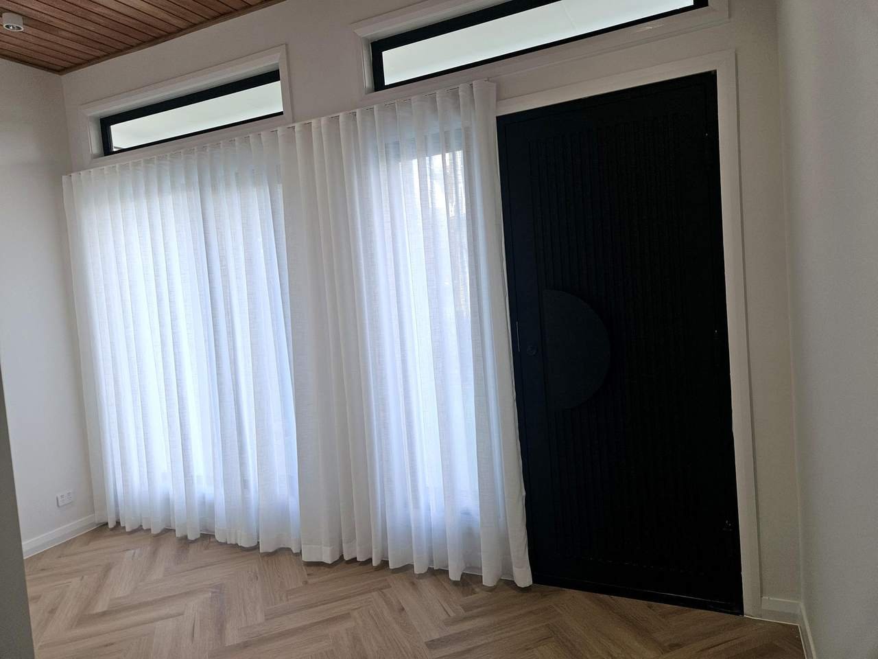 White sheer curtains beside a black feature door