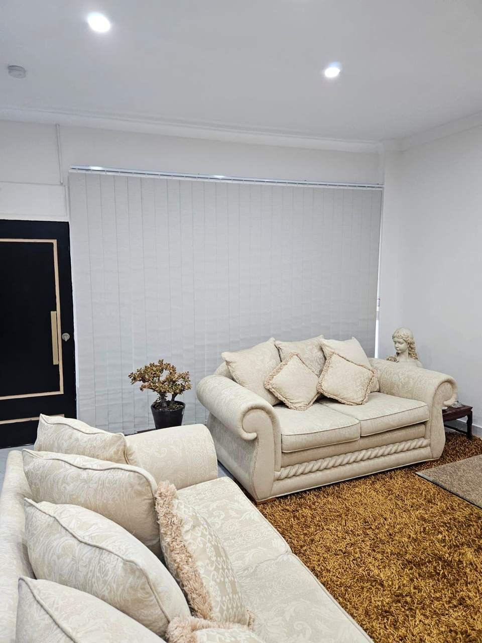 Light grey vertical blinds across a living room wall